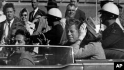 FILE - In this Nov. 22, 1963 file photo, President John F. Kennedy rides in a motorcade with his wife Jacqueline moments before he was shot and killed in Dallas, Texas.