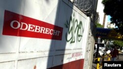 FILE - A man walks past the corporate logo of Odebrecht in a construction site in Caracas, Venezuela, Jan. 26, 2017.