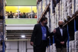 Orang-orang melihat dari jendela ketika Presiden AS Joe Biden mengunjungi Houston Food Bank didampingi oleh CEO-nya Brian Greene di Houston, Texas, AS, 26 Februari 2021. (Foto: REUTERS/Jonathan Ernst)