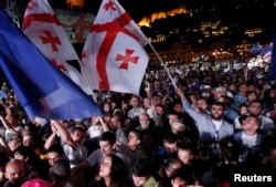 FILE - People wave Georgian and European flags during celebrations for the signing of an association agreement with the EU in Tbilisi, June 27, 2014.