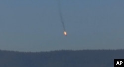 This frame grab from video by Haberturk TV, shows a Russian warplane on fire before crashing on a hill as seen from Hatay province, Turkey, Nov. 24, 2015.