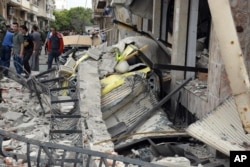 In this photo released by the Syrian official news agency SANA, Syrian citizens gather at the scene of an explosion in the central city of Homs, Syria.