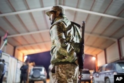 FILE - Libyan military soldier stands guard at the entrance of a town, 110 kilometers (68 miles) from Sirte, Libya.
