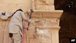 This image from a video posted April 3, 2015, shows a militant hammering at a face on a wall in Iraq's ancient city of Hatra.