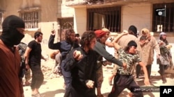 In this picture posted on a social media account affiliated with the Islamic State group, June 14, 2015, IS militants stone a man accused of violating the extremists' ban on homosexuality after they threw him from a roof in the city of Homs, Syria.