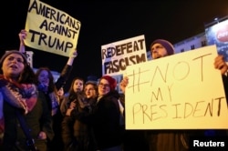 Anti-Trump protesters hold banners during a demonstration at Puerta del Sol Square in Madrid, Spain, Dec. 2, 2016.