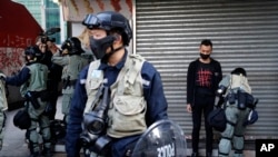 FILE - Police guard in front of a bus stop in Hong Kong, Dec. 9, 2019.