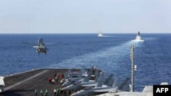 The aircraft carrier USS Abraham Lincoln transits the Strait of Hormuz as an MH-60S Sea Hawk helicopter lifts off from the flight deck, Nov. 19, 2019. 