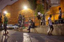 FILE - Migrants who are seeking seasonal work stand in a square in Lleida, Spain, July 2, 2020.