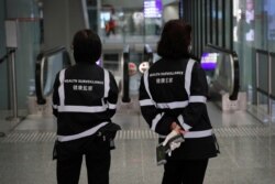 A health surveillance officer with temperature scanner waits for passengers at the Hong Kong International Airport, Jan. 4, 2020. Hong Kong authorities activated a new response protocol Saturday as fears spread about a mysterious infectious disease.