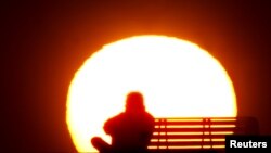 FILE - A man rests during sunset after a long and hot summer day at Dubai's popular Jumeirah beach.