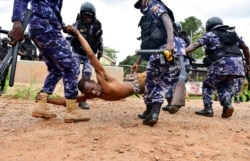 FILE - Riot policemen detain a supporter of presidential candidate Robert Kyagulanyi, also known as Bobi Wine, in Luuka district, Uganda, Nov. 18, 2020.