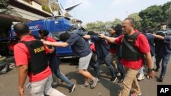 FILE - Police officers escort men arrested in a raid on a gay sauna at North Jakarta police headquarters in Jakarta, Indonesia, May 22, 2017. Indonesian police detained dozens of men in a weekend raid on a gay sauna in the capital.
