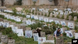 Yemeni men offer prayers at the grave of their relative who was killed during Yemen's ongoing conflict, at a cemetery in Sanaa, Yemen, July 3, 2020.