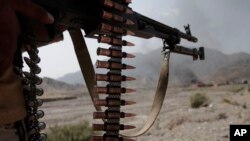FILE - An Afghan policeman stands guard near burning NATO supply trucks following an attack by militants on a U.S. base in the Torkham area near the Pakistan-Afghanistan border in Jalalabad province east of Kabul, Afghanistan, Sept. 2, 2013.