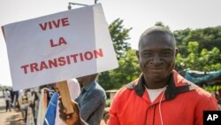 A supporter holds a placard in French reading "Long live the transition", outside where a ceremony to swear in the transitional president and vice president took place, in the capital Bamako, Mali, Sept. 25, 2020. 