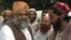 FILE - Maulana Fazl-ur-Rahman, left, leader of Pakistan's Jamiat Ulema-e-Islam party, is received by followers as he arrives in Pakistan at a border post near Lahore after a trip to India, July 24, 2003.