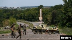 Ukrainian soldiers walk near a destroyed armored vehicle at Slovyansk, in eastern Ukraine, July 5, 2014. 