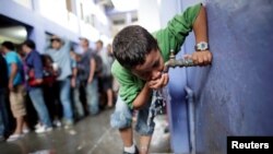 FILE - A migrant child drinks water from tap in Tecun Uman, Guatemala, October 19, 2018.