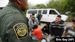 In this Thursday, March 14, 2019, file photo, a Border Patrol agent talks with a group suspected of having entered the U.S. illegally near McAllen, Texas. (AP Photo/Eric Gay, File)