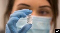 Seorang petugas medis menunjukkan ampul vaksin Covid-19 buatan Pfizer-BioNTech seiring dengan dimulainya program vaksinasi massal di Southmead Hospital di Bristol, Inggris, Selasa, 8 Desember 2020.