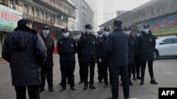 Security guards stand in front of the closed Huanan wholesale seafood market, where health authorities say a man who died from a respiratory illness, had purchased goods from, in the city of Wuhan, Hubei province, China, Jan. 12, 2020.