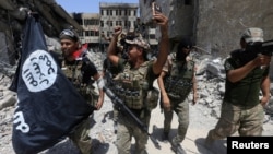 FILE - Members of the Emergency Response Division, the elite strike force of Iraq's Interior Ministry, hold an IS flag that they pulled down as they celebrate in Mosul, Iraq, July 8, 2017. Iraqi security forces continue to battle pockets of resistance across the country.