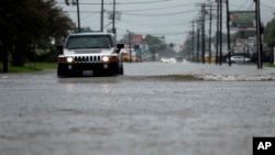 Cars drive through flooded streets in Lake Charles, La., as the city is hit with heavy rains from Tropical Storm Harvey, Aug. 27, 2017. The National Hurricane Center predicts a new tropical storm could form later this week, this time along the U.S. eastern seaboard.
