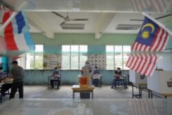 A woman castes a vote at a polling station during a state election on the outskirts of Kota Kinabalu, in Malaysia's Sabah state on Borneo island, Sept. 26, 2020.