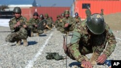 FILE - An Afghan soldier digs up a mine during a drill at Camp Shaheen, a training facility for the Afghan National Army, located west of Mazar-i-Sharif, Afghanistan, Dec. 13, 2014.