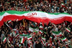 Iranian women cheer as they hold a huge Iranian flag during a soccer match between their national team and Cambodia in the 2022 World Cup qualifier at the Azadi (Freedom) Stadium in Tehran, Iran, Oct. 10, 2019.