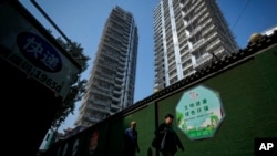 FILE - Residents walk by a luxury housing construction site in Beijing, Sept. 24, 2024. Over the past few months, regulators have rolled out a slew of policies meant to help reverse the downturn in the housing market and encourage more spending by Chinese households. 