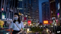 People wearing masks to protect against the coronavirus ride an escalator at a shopping and office complex in Beijing, July 16, 2020, as China's economy rebounded from a painful contraction to grow by 3.2% in the latest quarter compared to a year ago. 