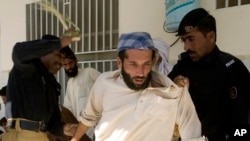 FILE - Pakistani police officers beat an internal displaced person who fled Pakistani tribal area of Waziristan due to fierce fight between security forces and militants, as they wait for food relief in Paharpur near Dera Ismail Khan, Pakistan, Oct. 22, 2009.