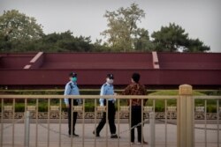 Chinese police officers wearing face masks to prevent the spread of the new coronavirus talk to a person near Tiananmen Square in Beijing, April 29, 2020.
