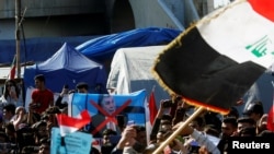 Iraqi demonstrators and university students carry posters depicting the newly appointed Prime Minister of Iraq, Mohammed Tawfiq Allawi, to express their rejection of him, during ongoing anti-government protests in Baghdad, Feb. 2, 2020. 