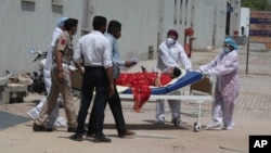 Health workers help a patient shift from a dedicated COVID-19 hospital to another hospital, in Ahmedabad, India, Thursday, April 15, 2021. India reported more than 200,000 new coronavirus cases Thursday. (AP Photo/Ajit Solanki)