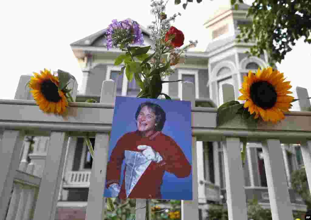 A photo of the late actor Robin Williams as Mork from Ork hangs with flowers left by people paying their respects, in Boulder, Colorado, Aug. 11, 2014, at the home where his hit 1980s TV series "Mork & Mindy", was set. 