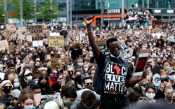 A man raises his fist as people gather in Berlin, Germany, June 6, 2020, to protest the recent killing of George Floyd.