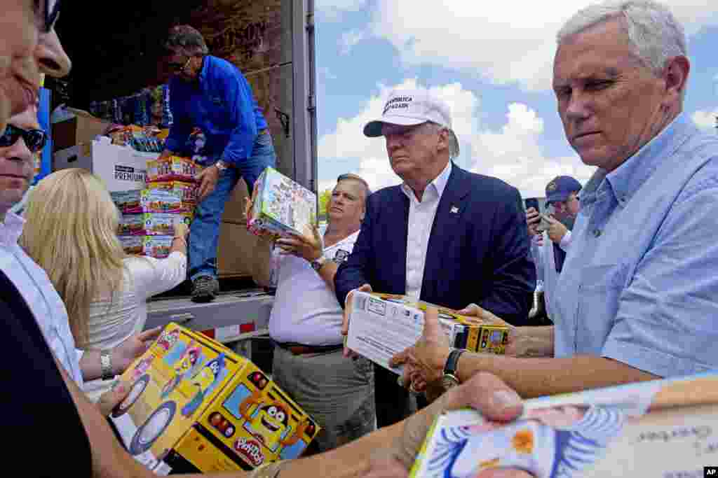 Republican presidential candidate Donald Trump and his running mate, Indiana Gov. Mike Pence, right, help to unload supplies for flood victims during a tour of the flood damaged area in Gonzales, Louisiana, Aug. 19, 2016. 