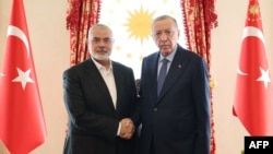 This handout photograph taken and released by Turkish Presidency Press Office on April 20, 2024, shows Turkish President Recep Tayyip Erdogan, right, shaking hands with Ismail Haniyeh, the political leader of Hamas, at the Dolmabahce Presidential working office in Istanbul.