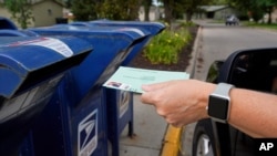 FILE - A person drops applications for mail-in ballots into a mailbox in Omaha, Nebraska, Aug. 18, 2020.