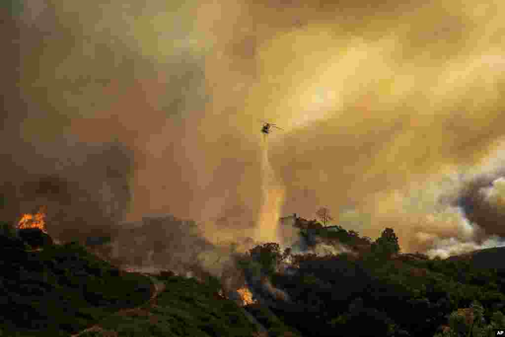 Water is dropped on the advancing Palisades Fire by helicopter in the Pacific Palisades neighborhood of Los Angeles, Jan. 7, 2025.