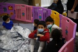 Young unaccompanied migrants, ages 3-9 sit inside a playpen at the Donna Department of Homeland Security holding facility, the main detention center for unaccompanied children in Donna, Texas, March 30, 2021.