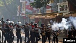 Riot police officers fire teargas canisters during a protest against the military coup in Yangon, Myanmar, Feb. 28, 2021.