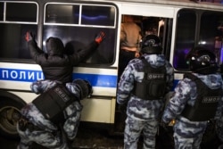 FILE - A riot police officer searches a detained man during a protest against a court ruling ordering Russian opposition leader Alexey Navalny jailed for nearly three years, in downtown Moscow, Feb. 3, 2021.