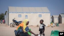 FILE - A displaced Burkinabe woman and child prepare food, in the Pissila town camp, near Kaya, Burkina Faso, Dec. 10, 2019. 