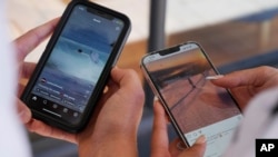 FILE - Fourteen-year-old Henry, left, and Angel, 15, view social media on their phones in Sydney, Australia, Nov. 8, 2024. In Australia, a high-profile social media ban for young adults under the age of 16 will take effect at the end of 2025.