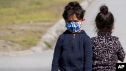 Migrant children wearing face masks to protect against coronavirus play near a refugee center near Belgrade, Serbia, March 26, 2021. 