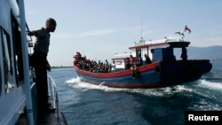 FILE - Police guard a wooden boat carrying ethnic Rohingya refugees from Myanmar. Australian officials say their policies have prevented asylum seekers from risking their lives at sea trying to reach Australia by boat.